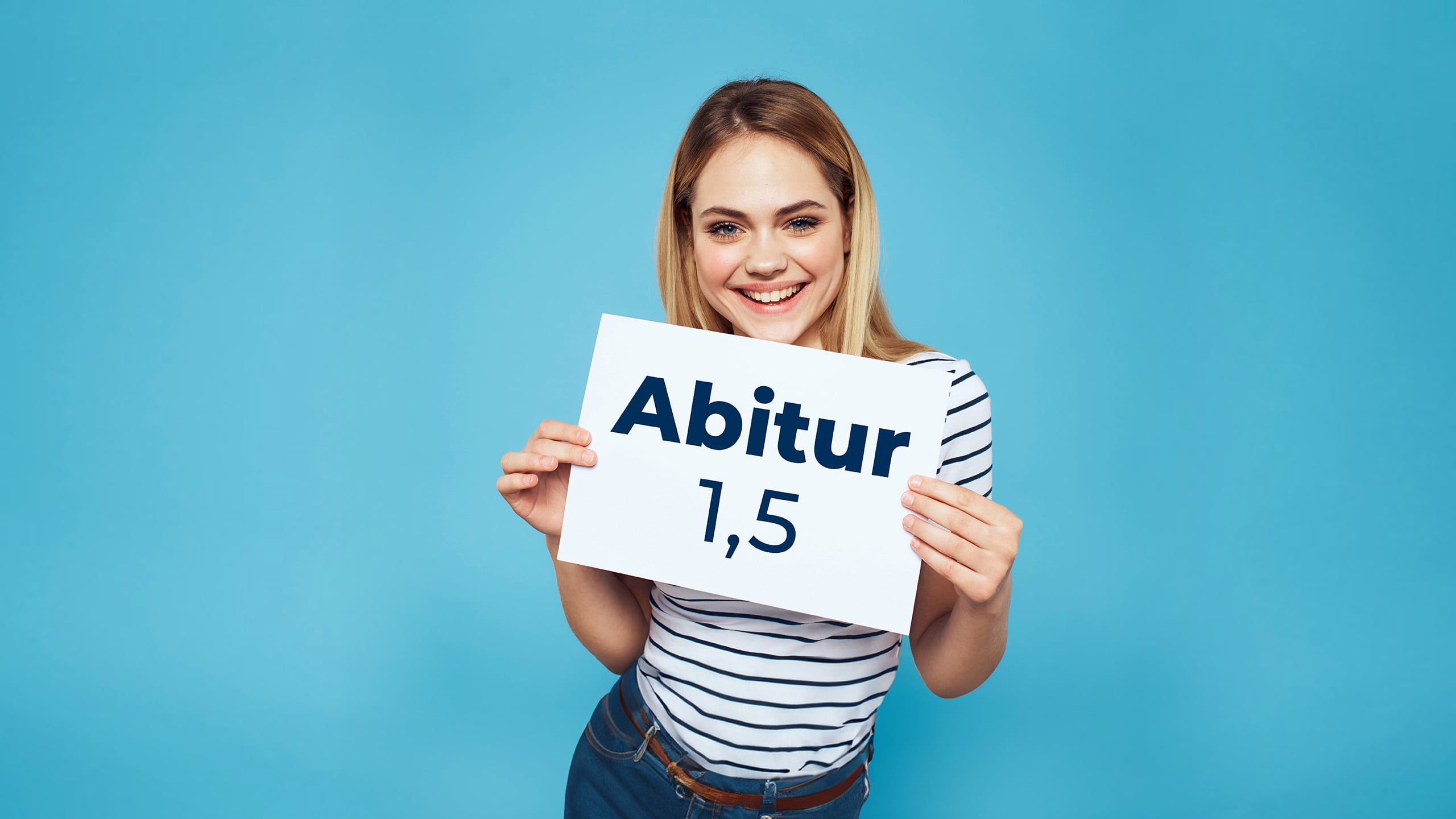 Eine junge Frau hält lächelnd ein Schild in der Hand, auf dem Abitur 1,5 steht.